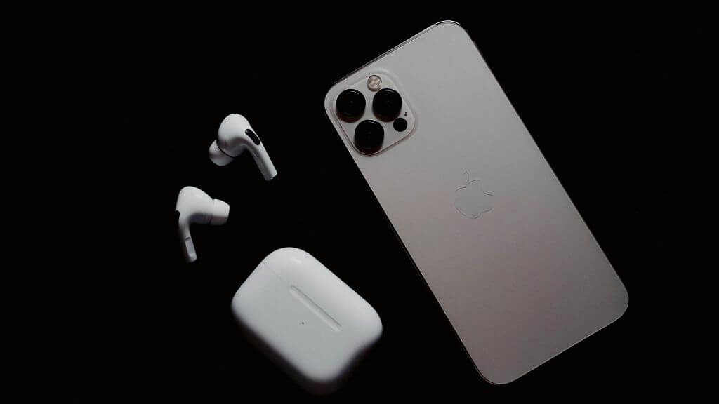 جهاز iPhone مقلوب بجوار AirPods وحافظتها.