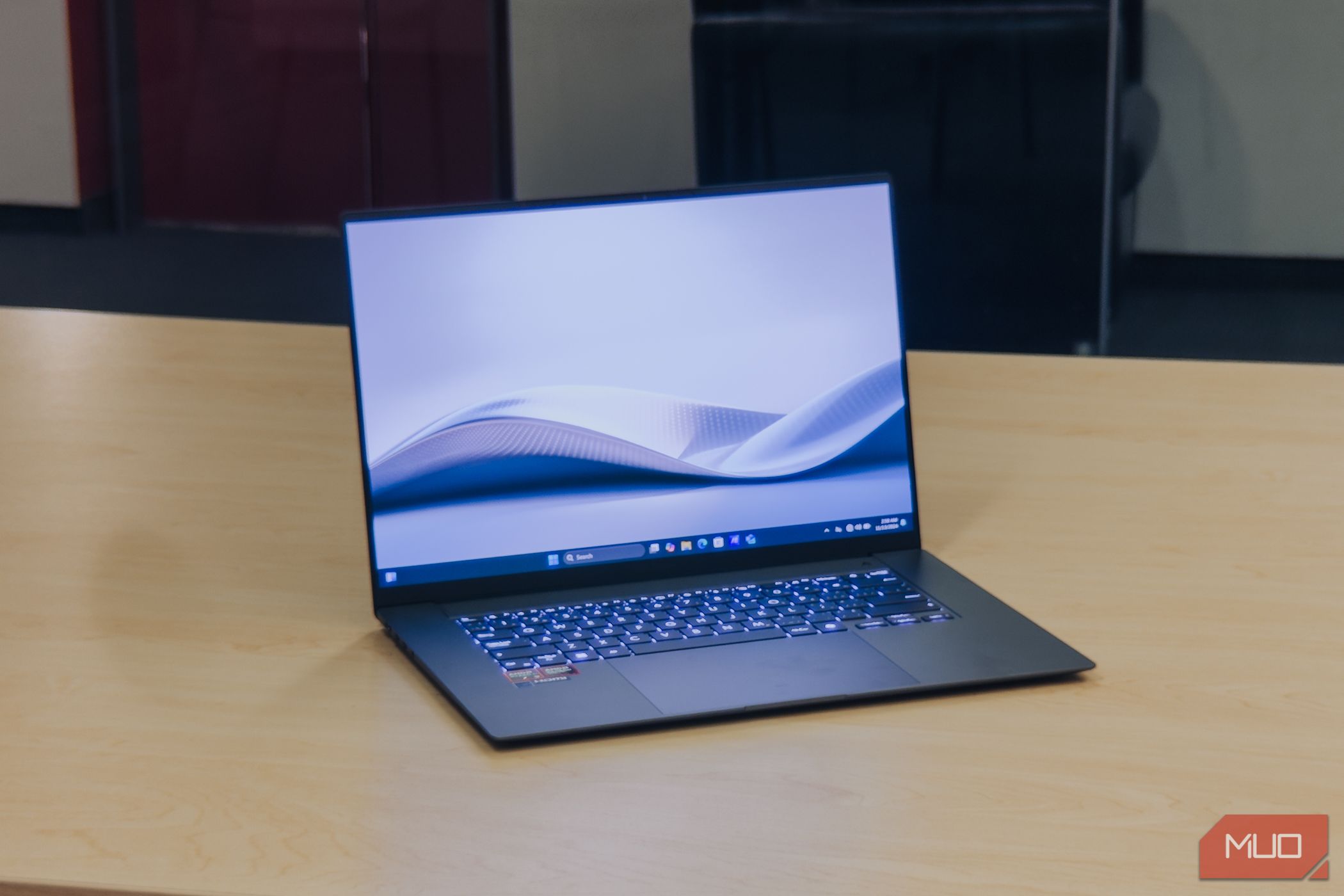 Asus Zenbook S 16 على شاشة بزاوية على طاولة خشبية.