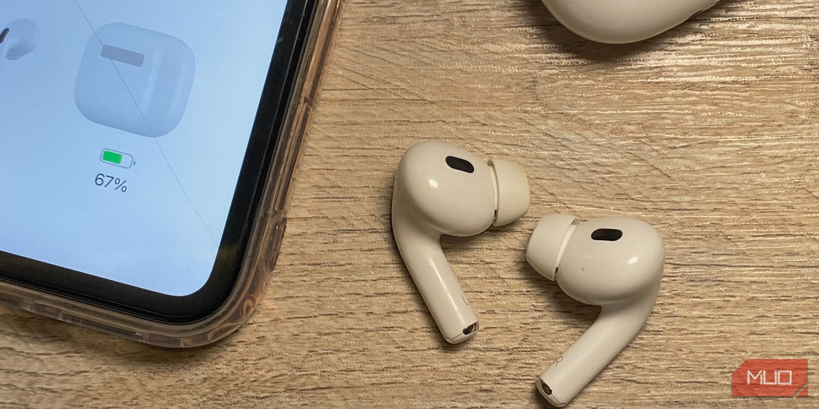 airpods على طاولة خشبية إلى جانب iPhone