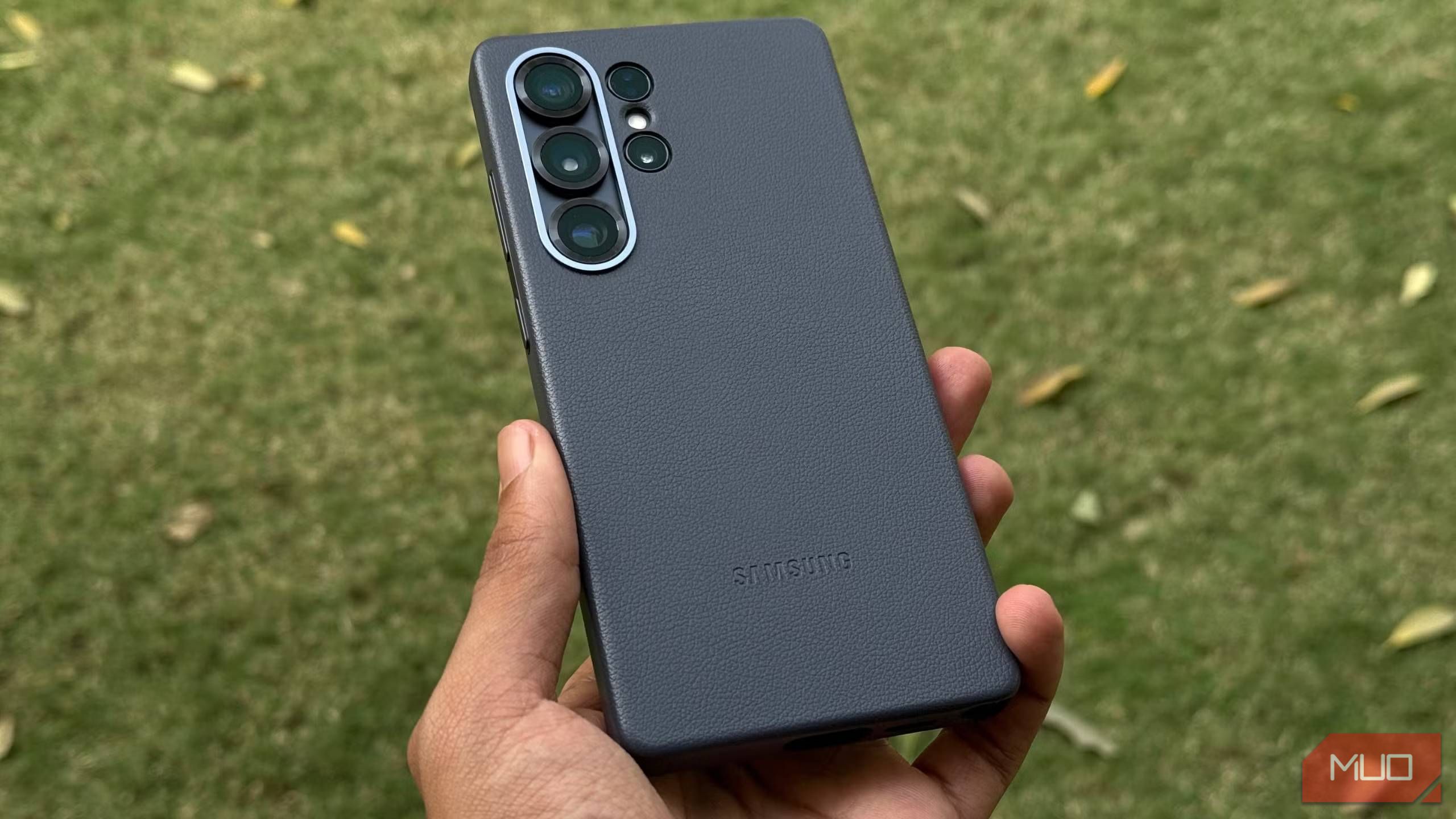 Galaxy S25 Ultra Blackuit Suiture Case الذي تم وضعه في متناول اليد مع العشب في الخلفية